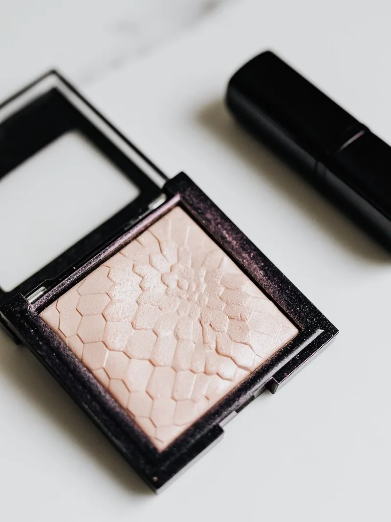 Highlighter padat berwarna merah muda pucat dalam wadah hitam