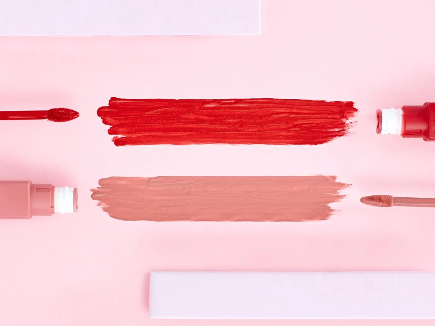 Usapan pewarna bibir merah dan merah muda di atas latar merah jambu